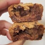 Image shows A person holding up two halves of candy bar stuffed cookies.