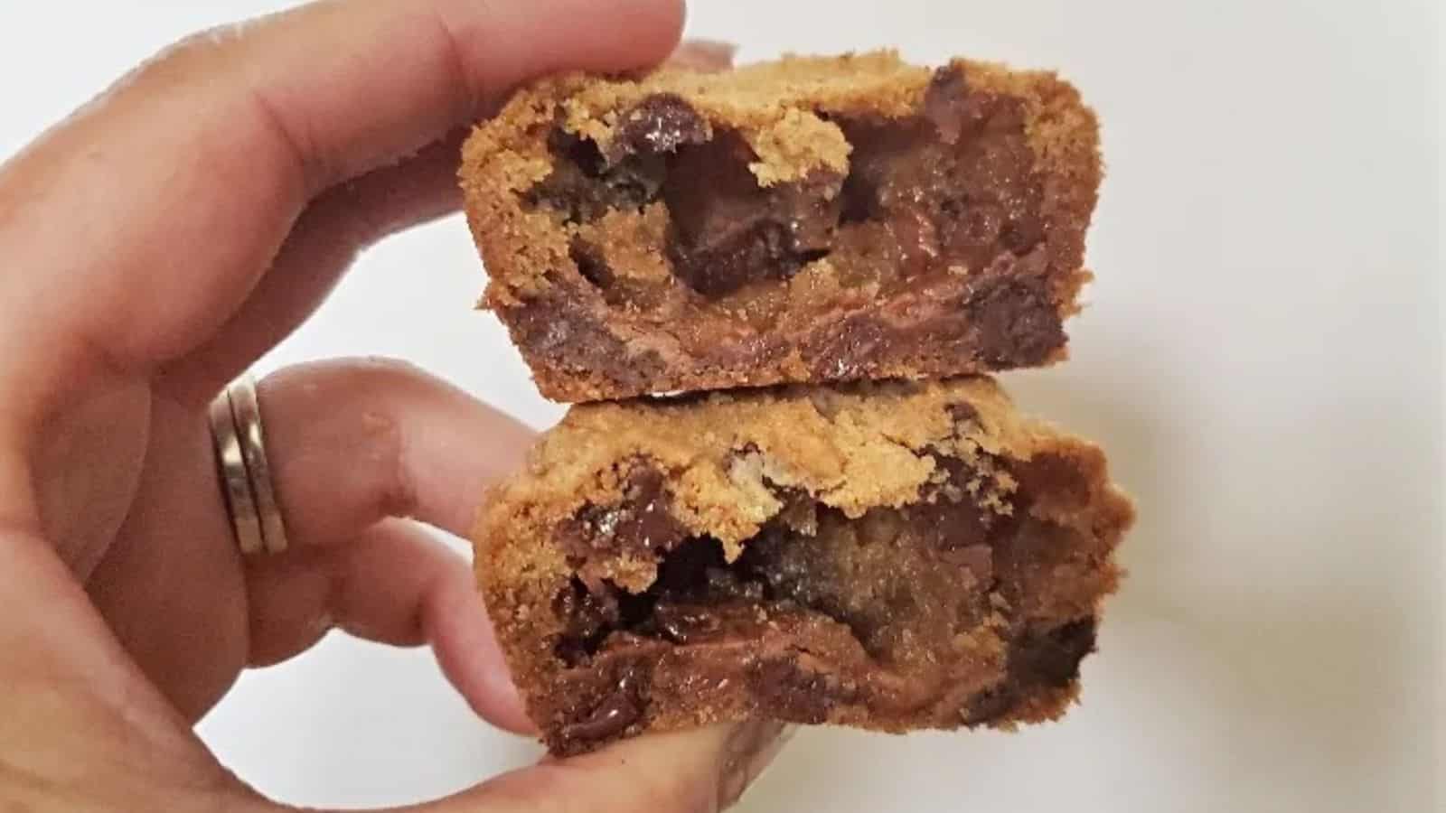 Image shows A person holding up two halves of candy bar stuffed cookies.