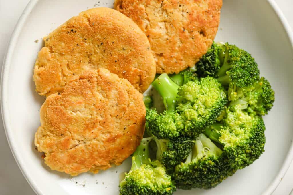 A plate with broccoli and chicken patties on it.