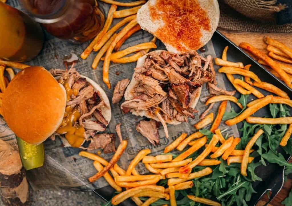 Bbq pulled pork sandwich and french fries on a tray.