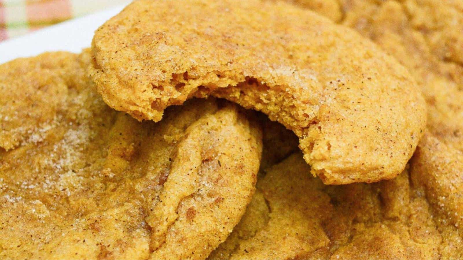Pumpkin snickerdoodles cookies on a plate with a bite taken out of them.
