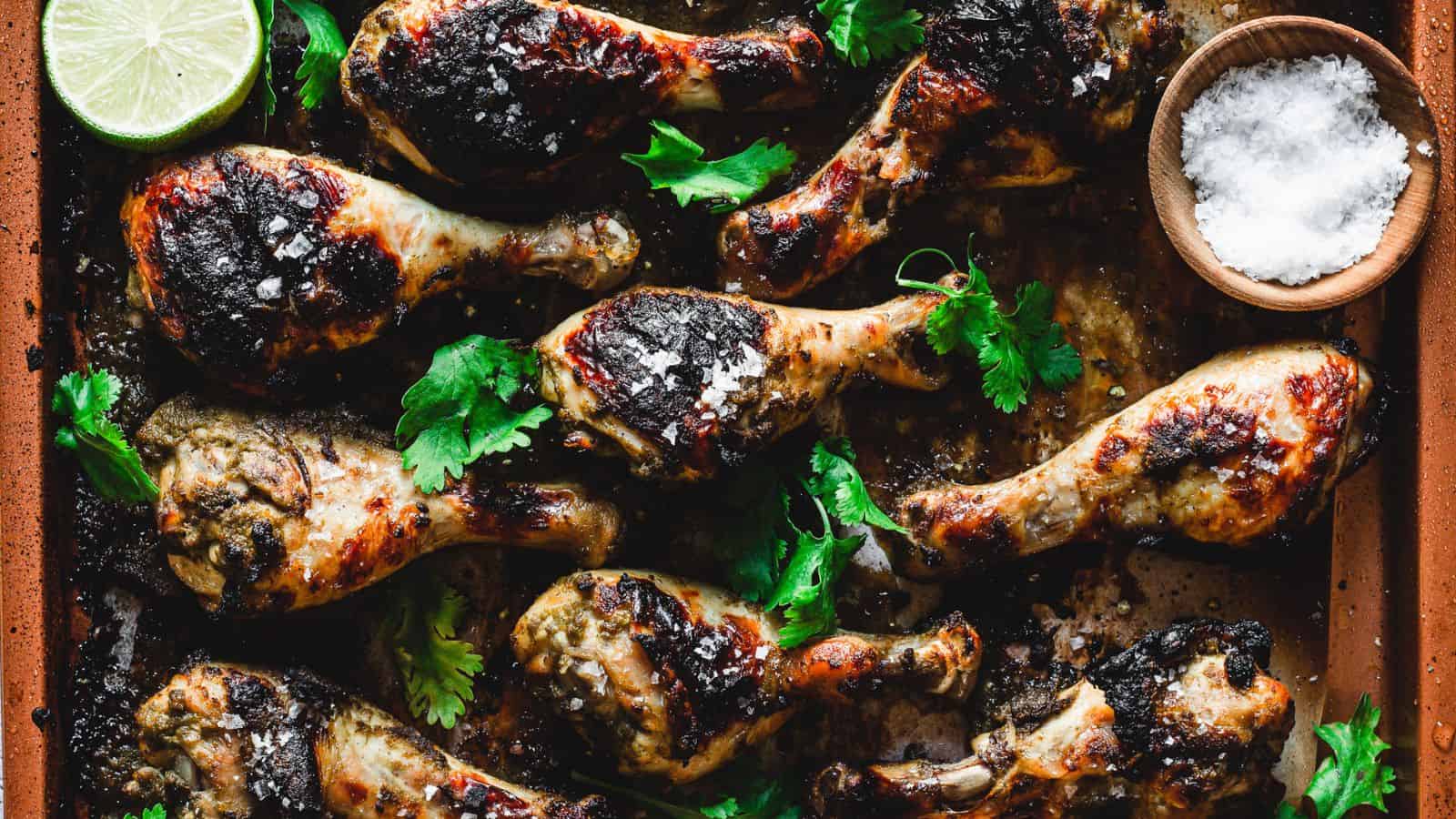 Chicken drumsticks on baking sheet with salt and lime.