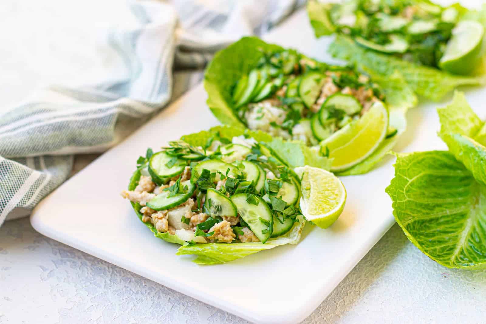 Thai chicken lettuce wraps with peanut sauce on a white plate.