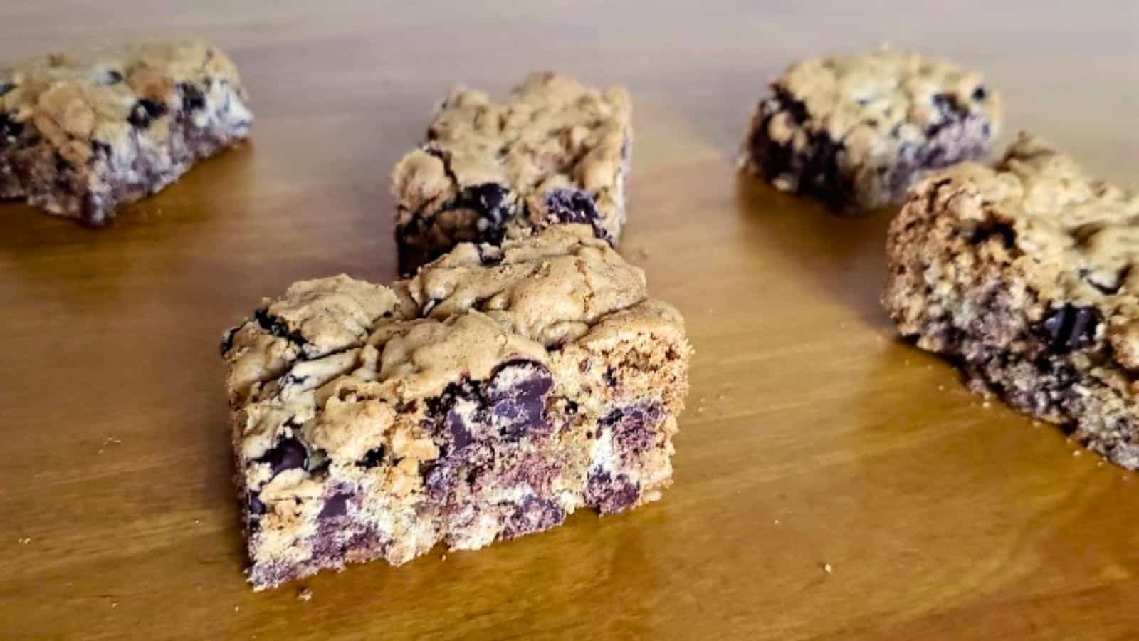 Image shows A group of chocolate chip oat bars on a wooden table.