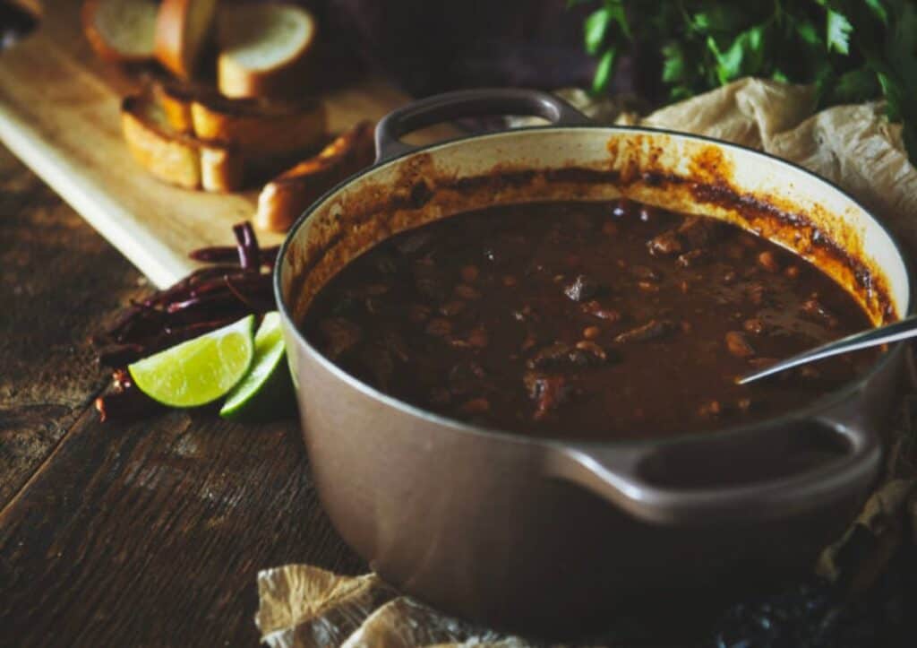 A pot of chili on a wooden table.