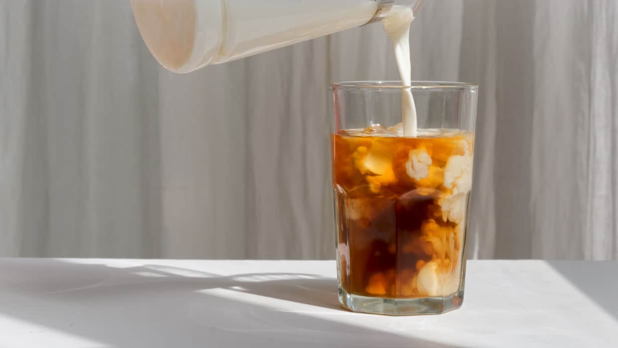 An iced coffee being poured.