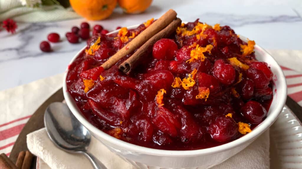 A bowl of cranberry sauce with oranges and cinnamon.