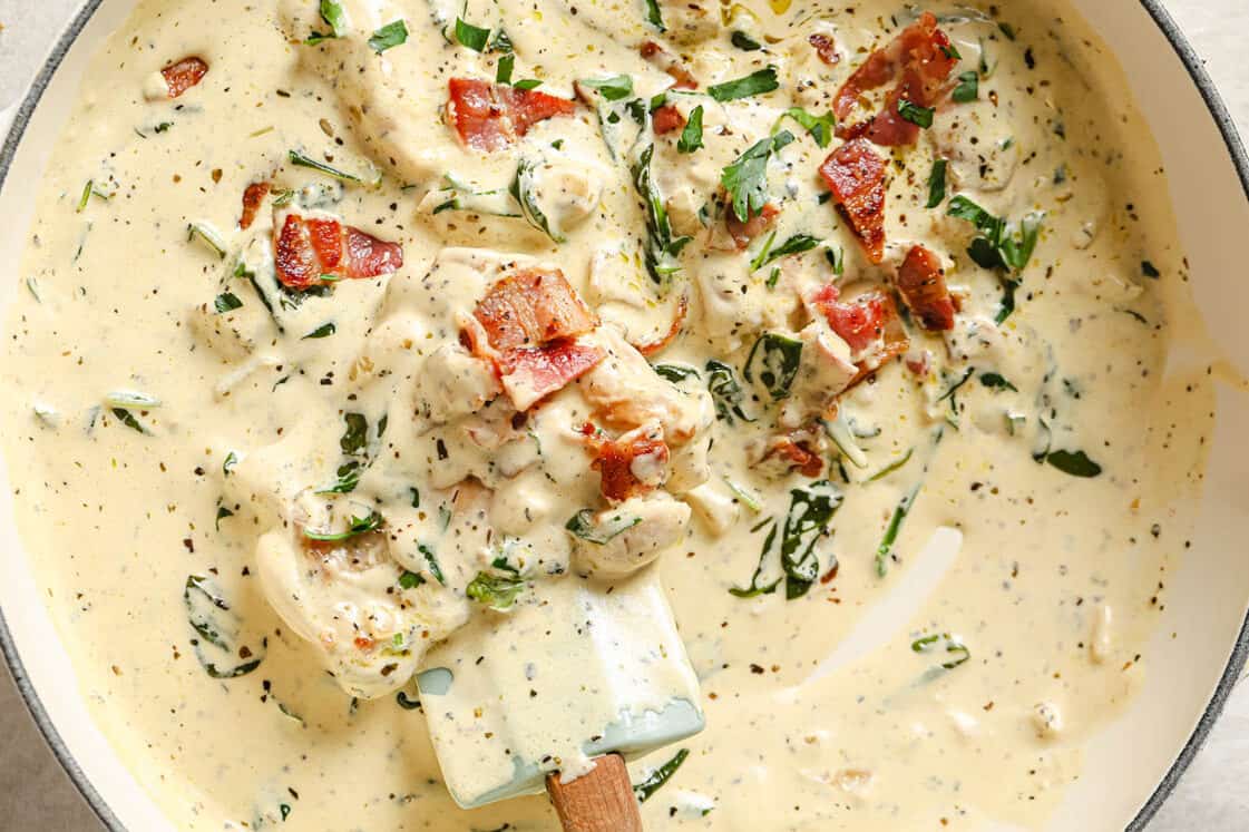 A pan of creamy dijon chicken with herbs and bacon.