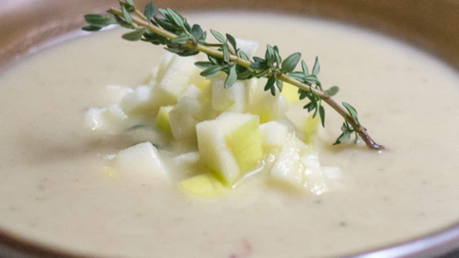 A bowl of soup with apples and sprigs of thyme.