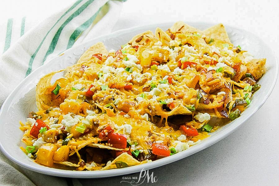 Tortilla chips on a platter with fish, peppers, and cheese.