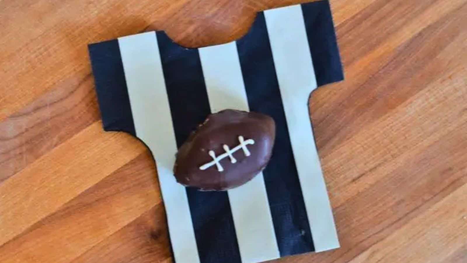 Image shows an overhead view of a football shaped oreo cookie ball on a referee striped napkin.