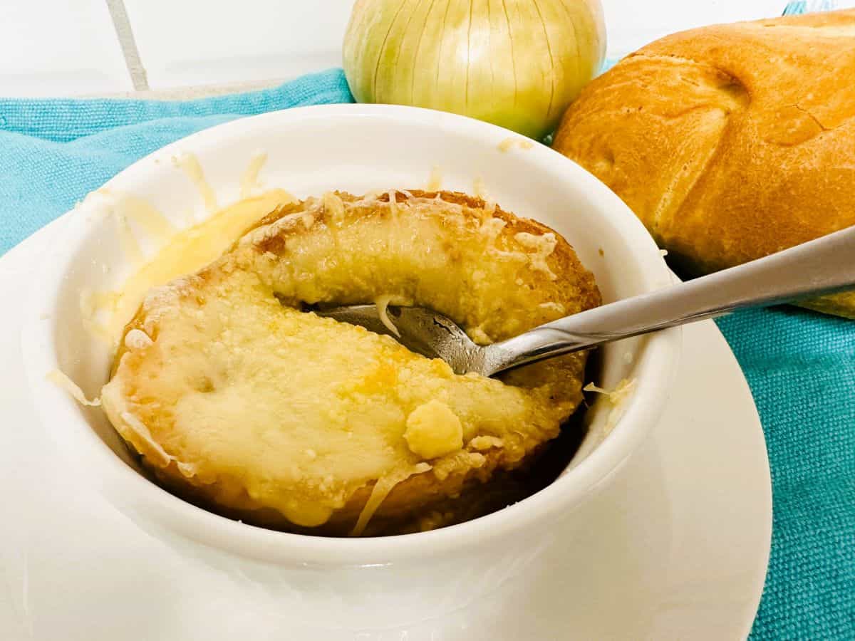 A bowl of French onion soup with a spoon next to it.