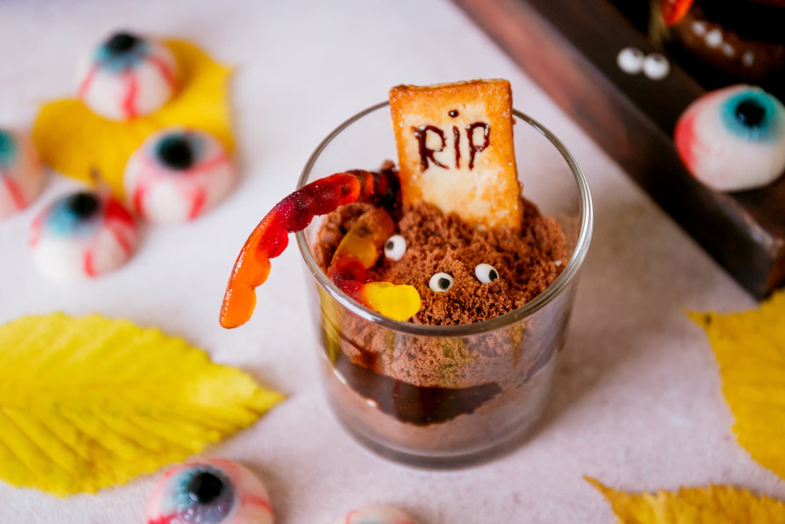 A glass of Halloween graveyard chocolate pudding with tombstone cookie on top that reads RIP.