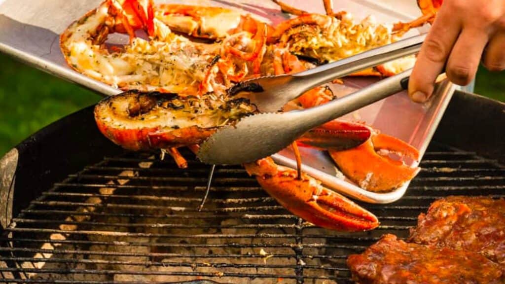 A person is grilling lobsters on a grill.