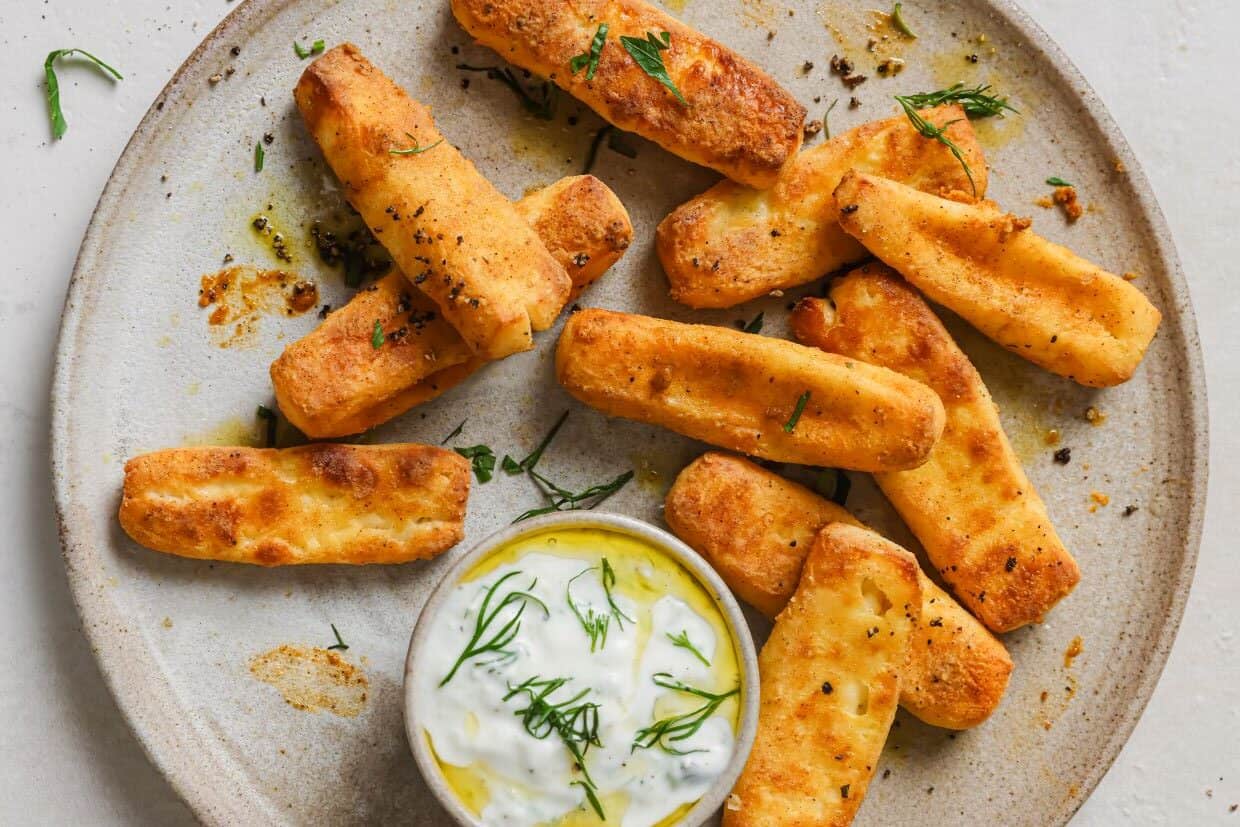 Halloumi fries with dill dip on a plate.