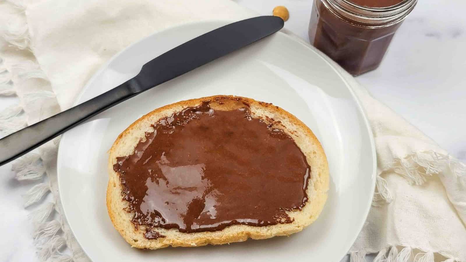 A plate with a slice of toast spread with homemade dairy-free hazelnut spread.