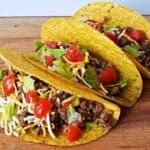 Image shows three honey habanero tacos on a wooden table.