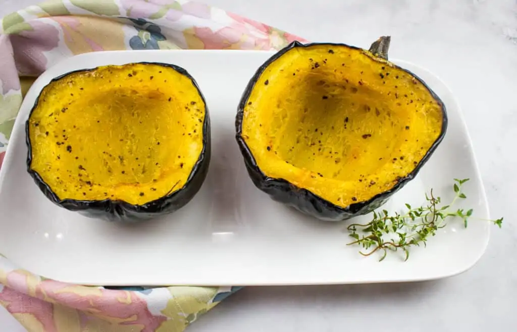 Two halves of Baked Acorn Squash with Maple Sryup on a white plate.