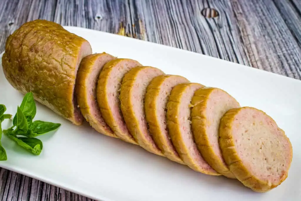 Smoked Breakfast Sausage on a white plate with basil leaves.