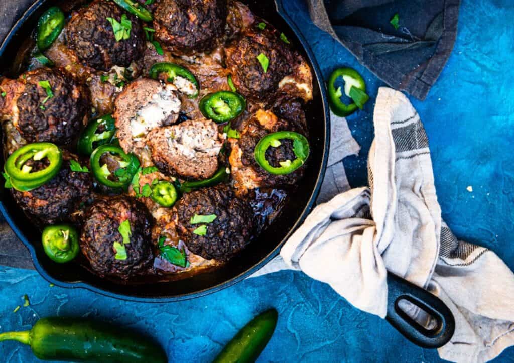 A skillet filled with meatballs and jalapenos.