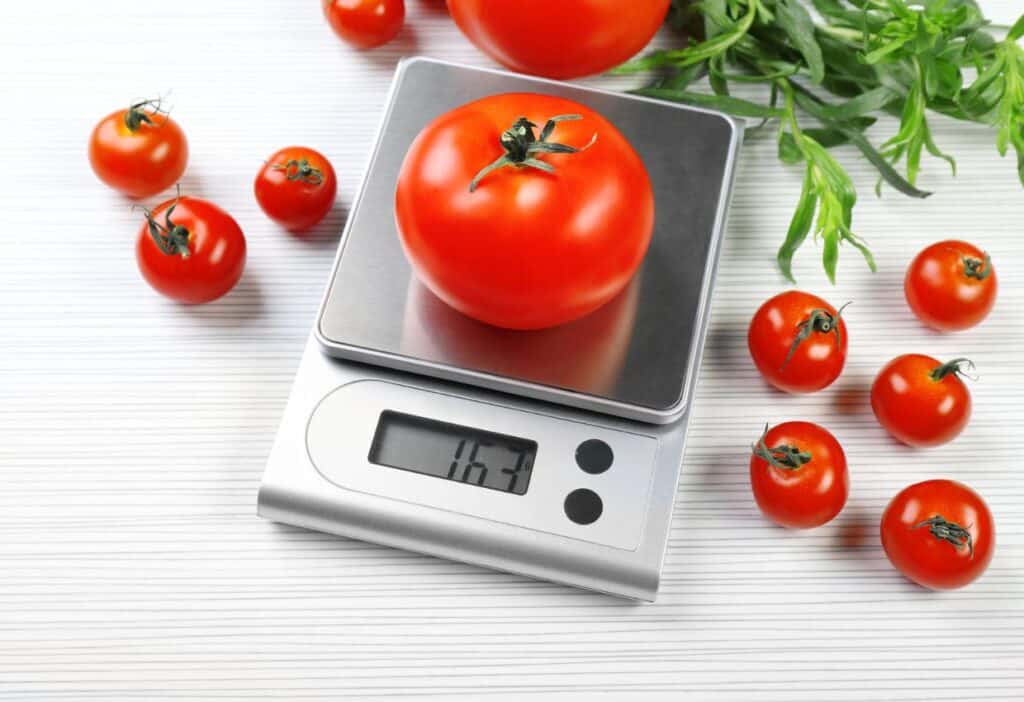 A digital scale with tomatoes on it.
