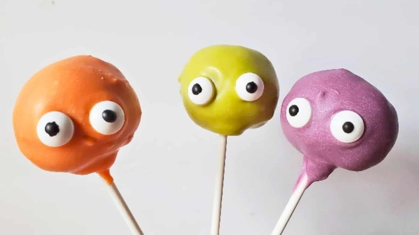 Image shows three monster cake pops in various colors against a white background.