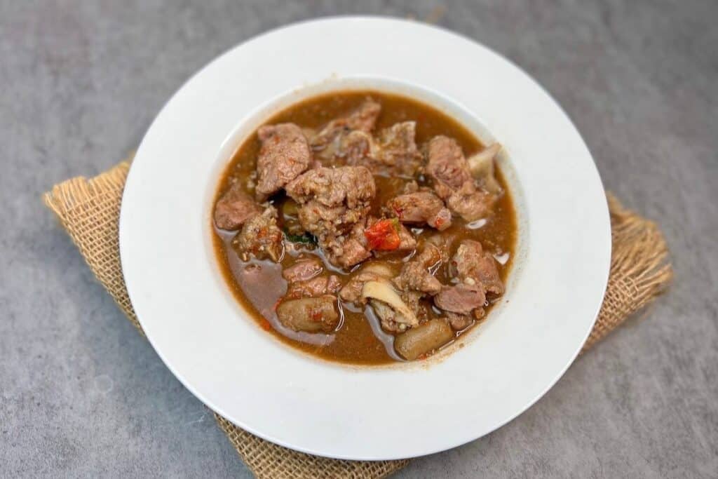 A white bowl of stew with meat and vegetables.