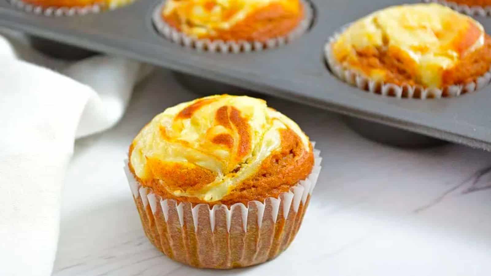 Pumpkin cream cheese muffin with a bite taken out of it.