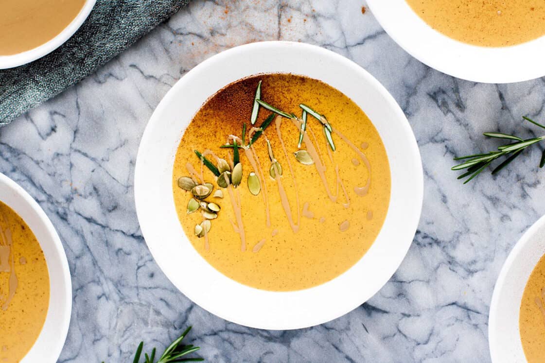 Bowls of pumpkin soup with sprigs of rosemary.