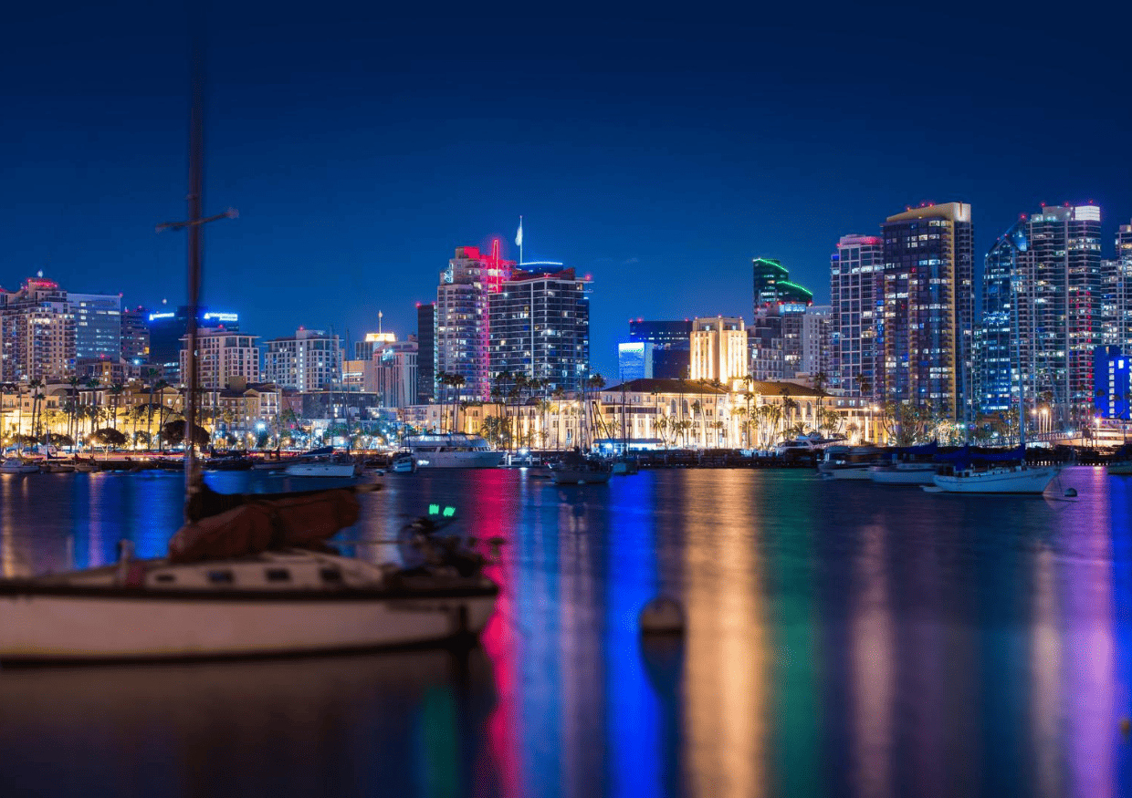 The city of san diego at night with boats in the water.