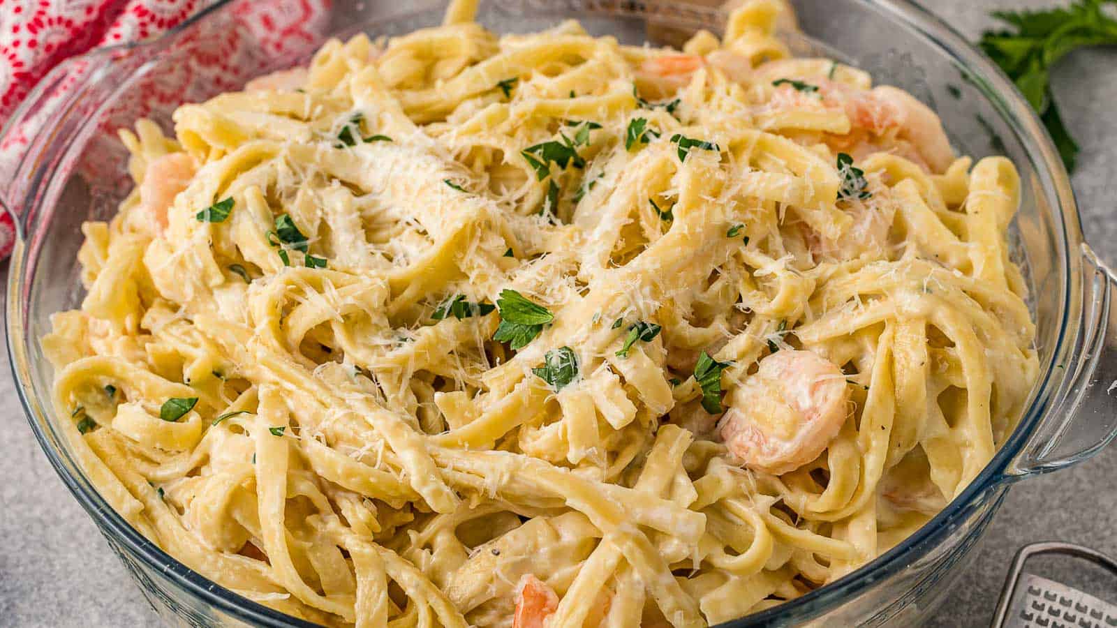 Shrimp and fettuccine pasta in a large glass bowl.