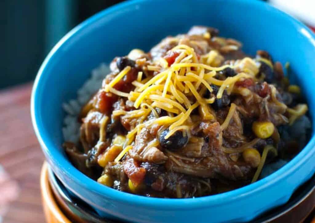 A bowl of chili with rice and corn.