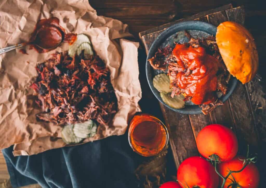 Bbq chuck roast and tomatoes on a wooden table.
