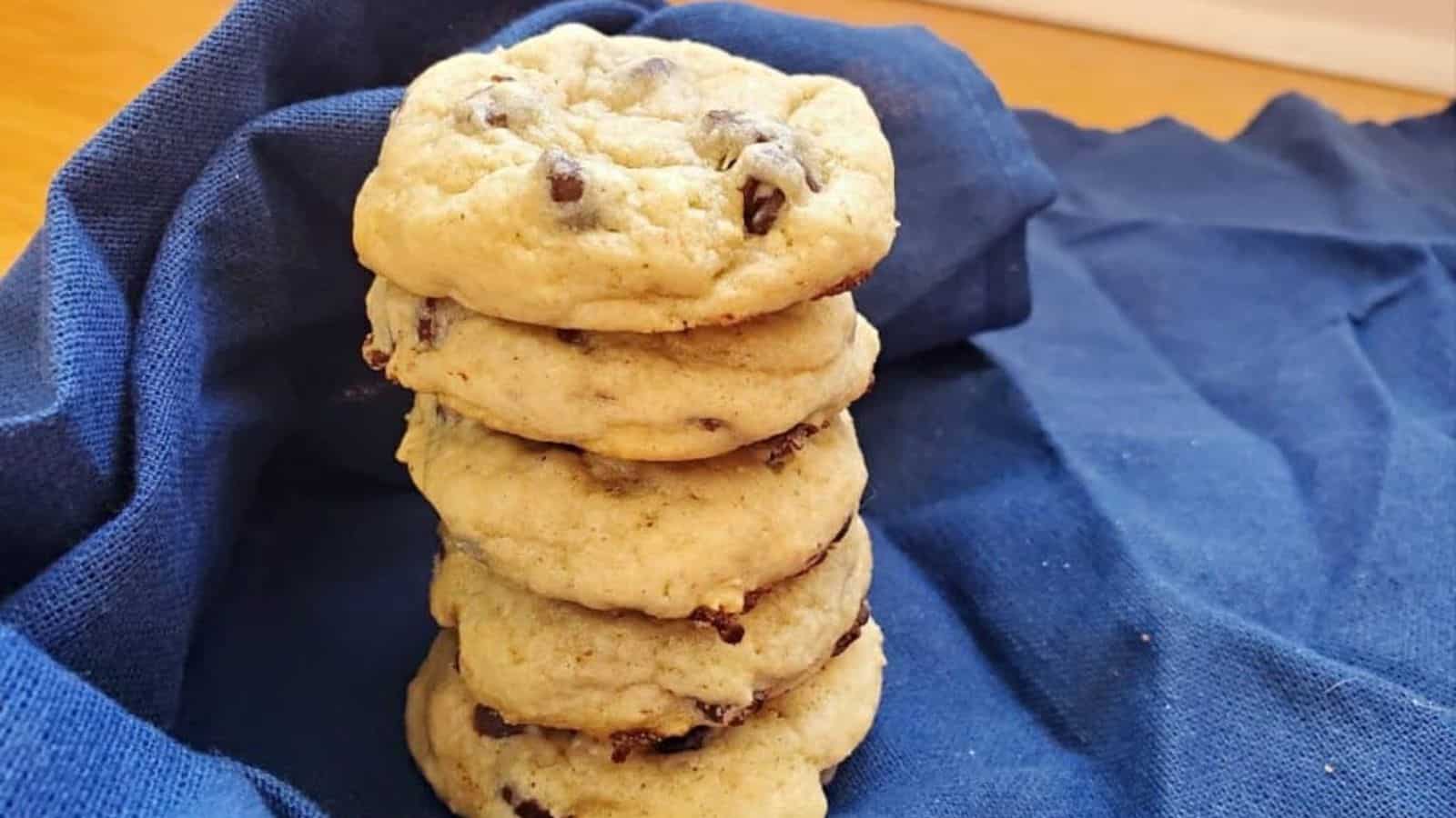 Image shows A stack of sourdough chocolate chip cookies on a blue cloth.