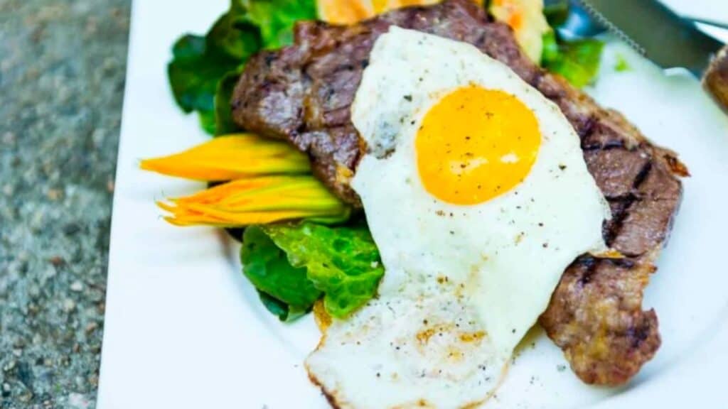 A steak with an egg and vegetables on a plate.