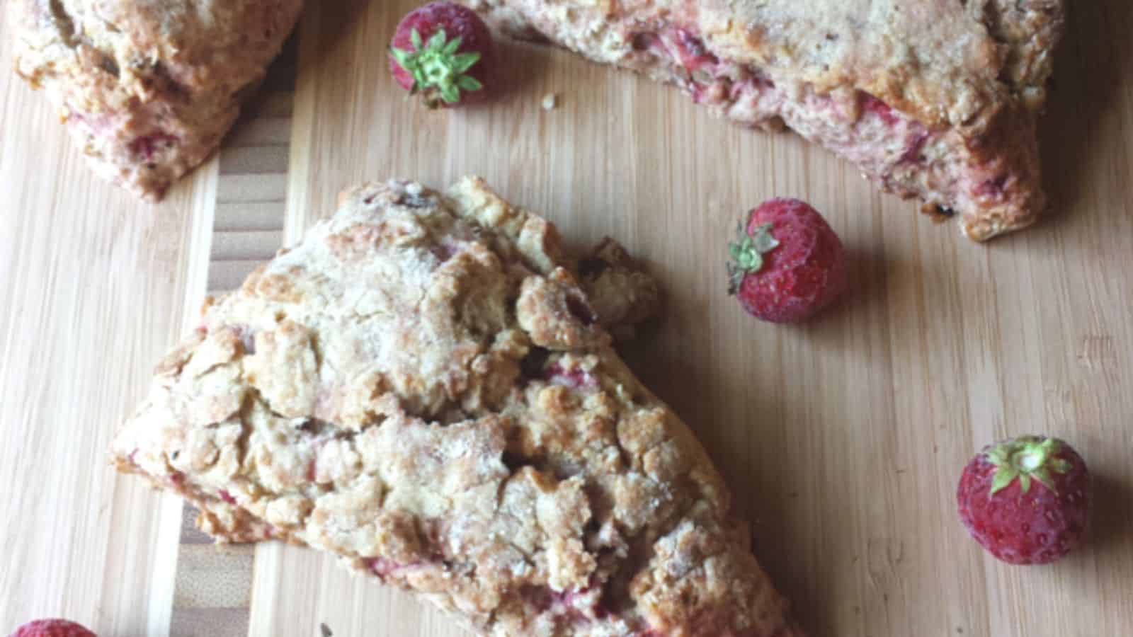 Image shows an overhead shot of Strawberry bacon scones on a wooden cutting board.