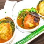 Three plates of cabbage rolls with sauce on a white plate.