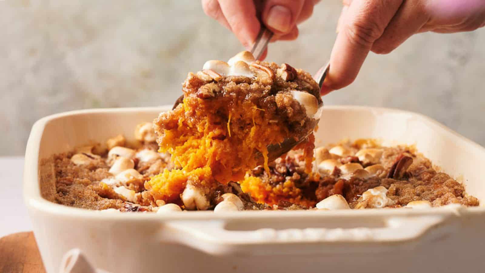 A person scooping a sweet potato casserole out of a baking dish.
