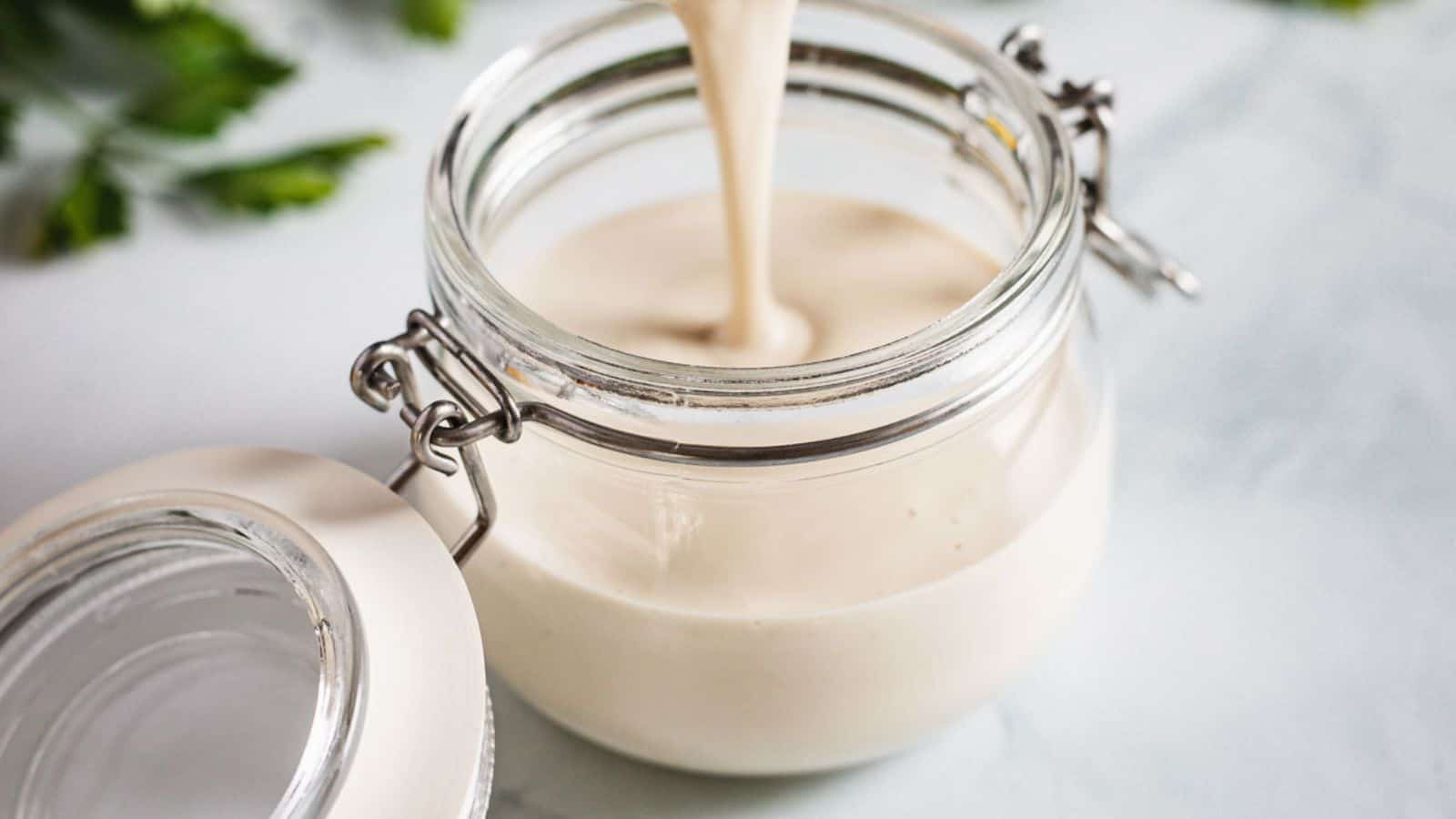 A jar with a white sauce pouring out of it.