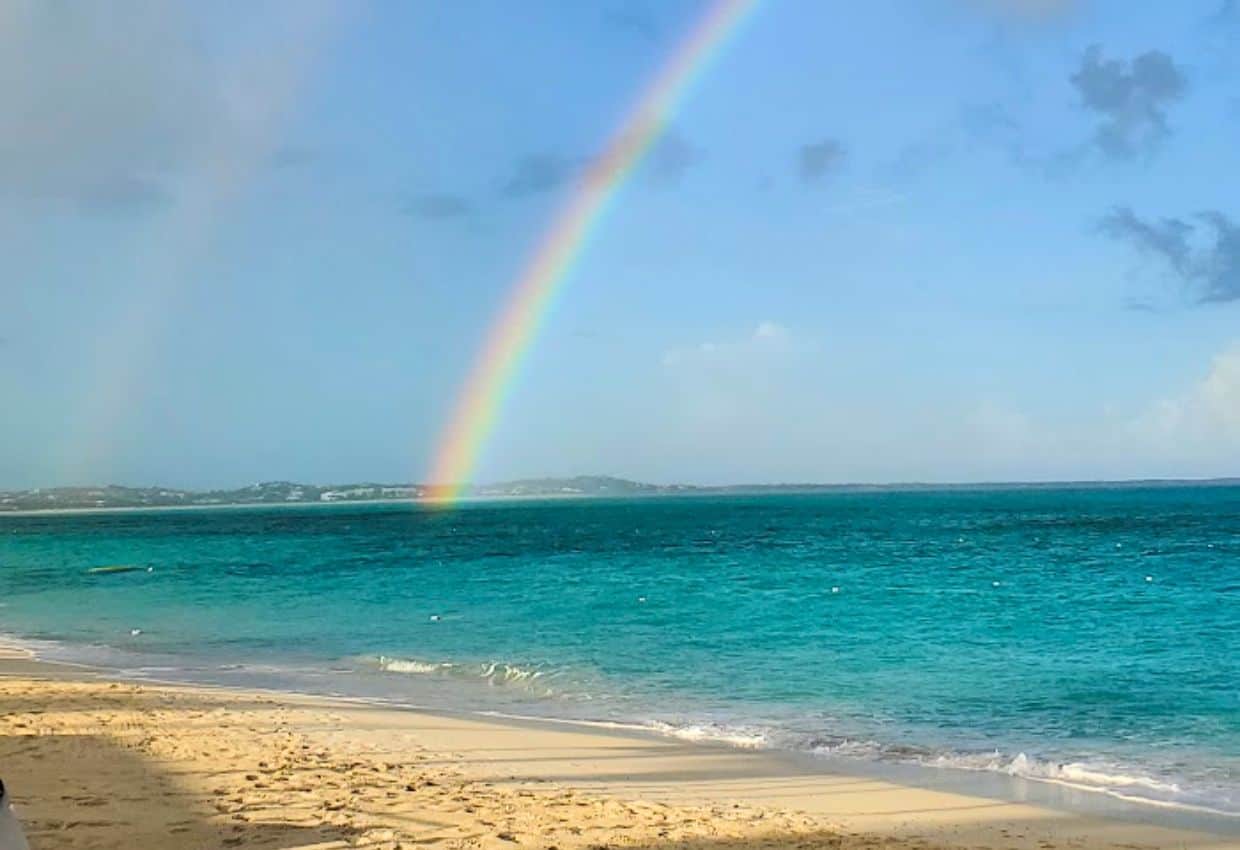 Image shows a Turks and Caicos beach with a rainbow.