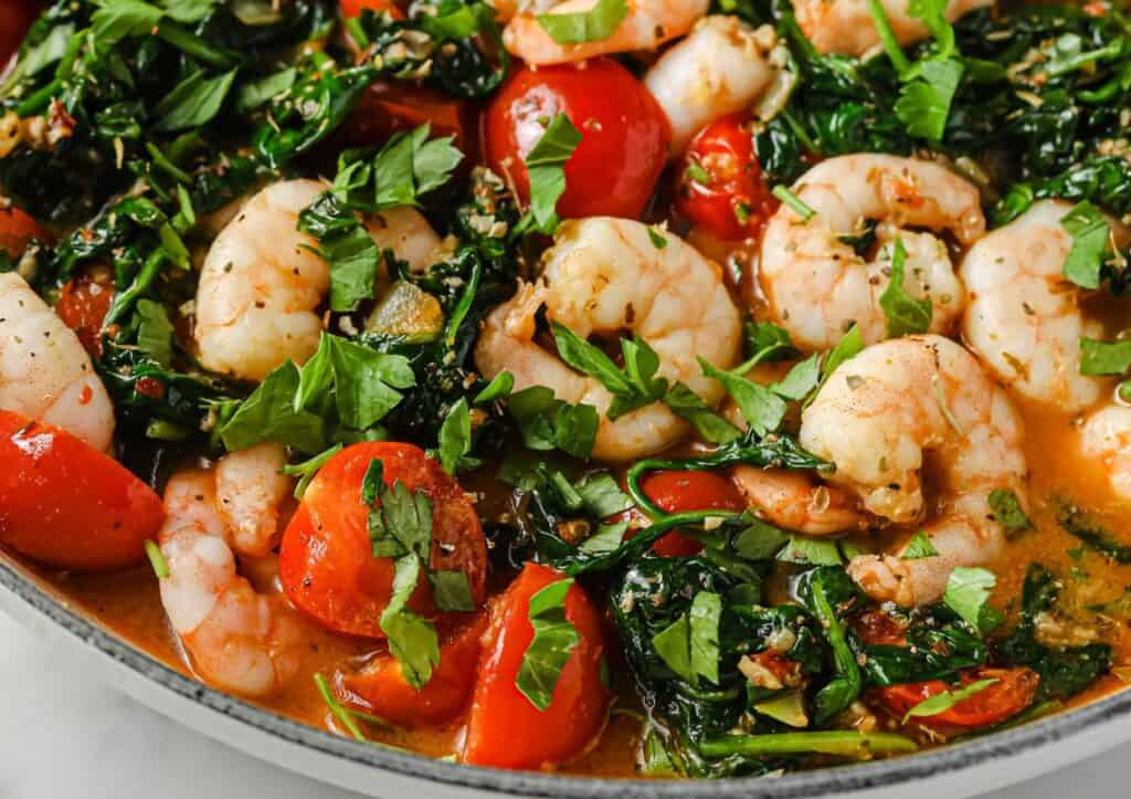 Tuscan garlic shrimp with spinach and tomatoes in a pan.
