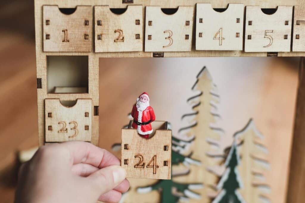 A person displaying a wooden santa claus advent calendar.