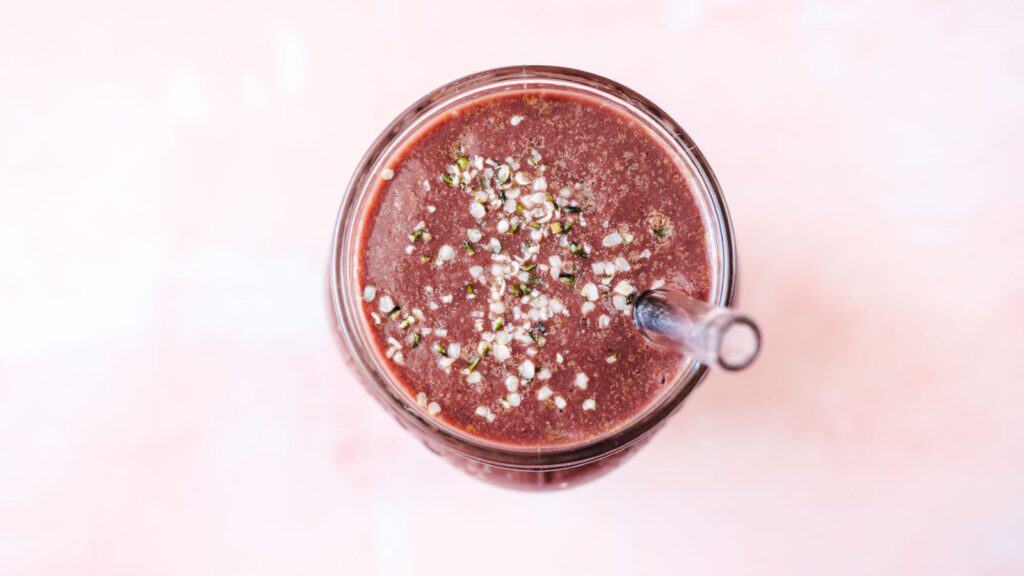 A delicious smoothie with berries and seeds showcased against a vibrant pink backdrop.