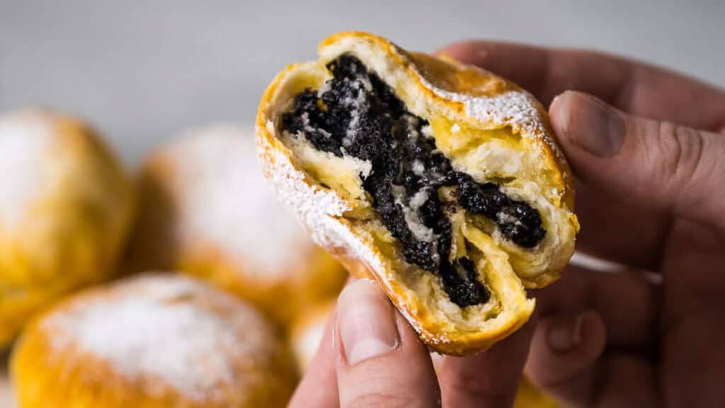 A person holding a pastry with an oreo filling.