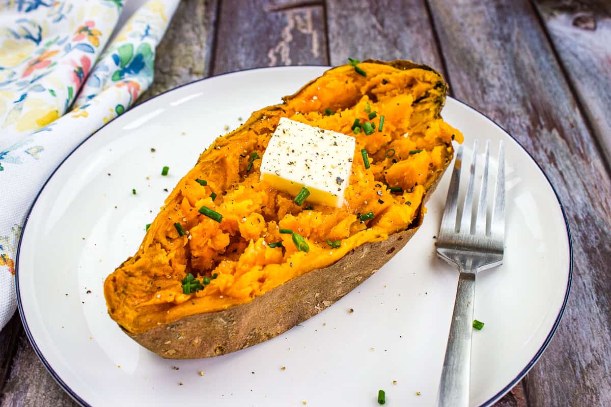 A sweet potato on a plate with a fork.
