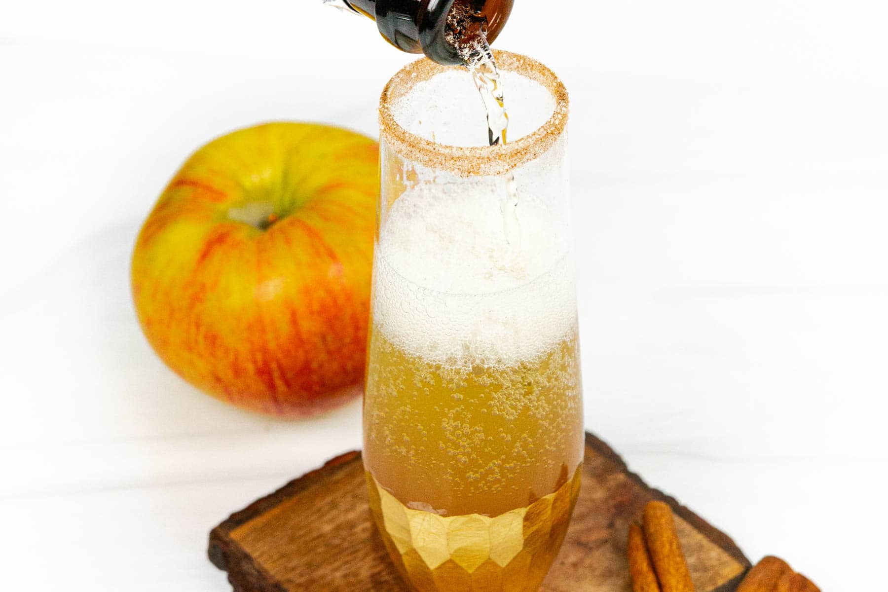 Champagne being poured into a glass of apple cider.
