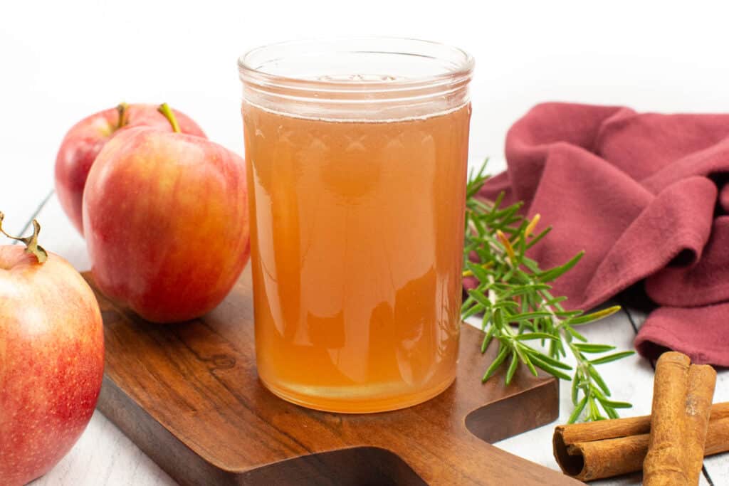 Ingredients for apple simple syrup sitting around a jar of completed syrup.