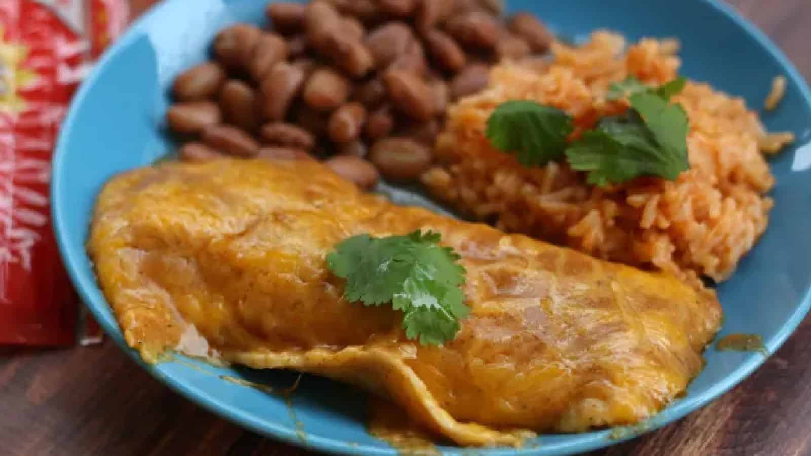 Blue plate with a cheese enchilada, rice, and beans.