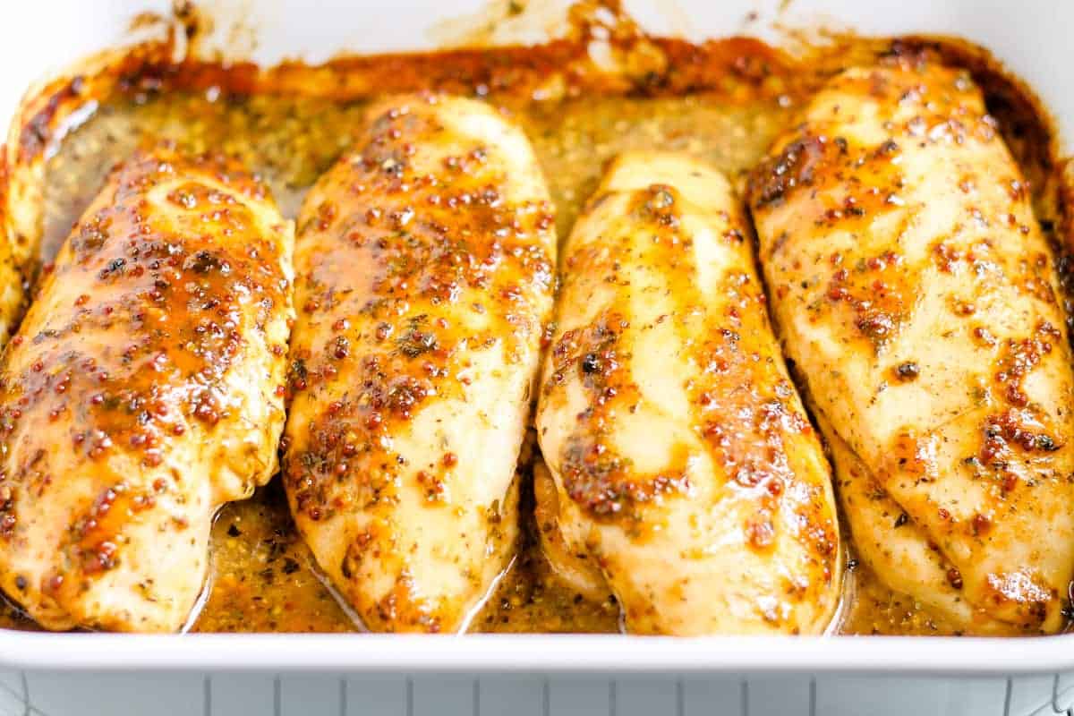 A baking dish with 4 breasts of honey mustard chicken.