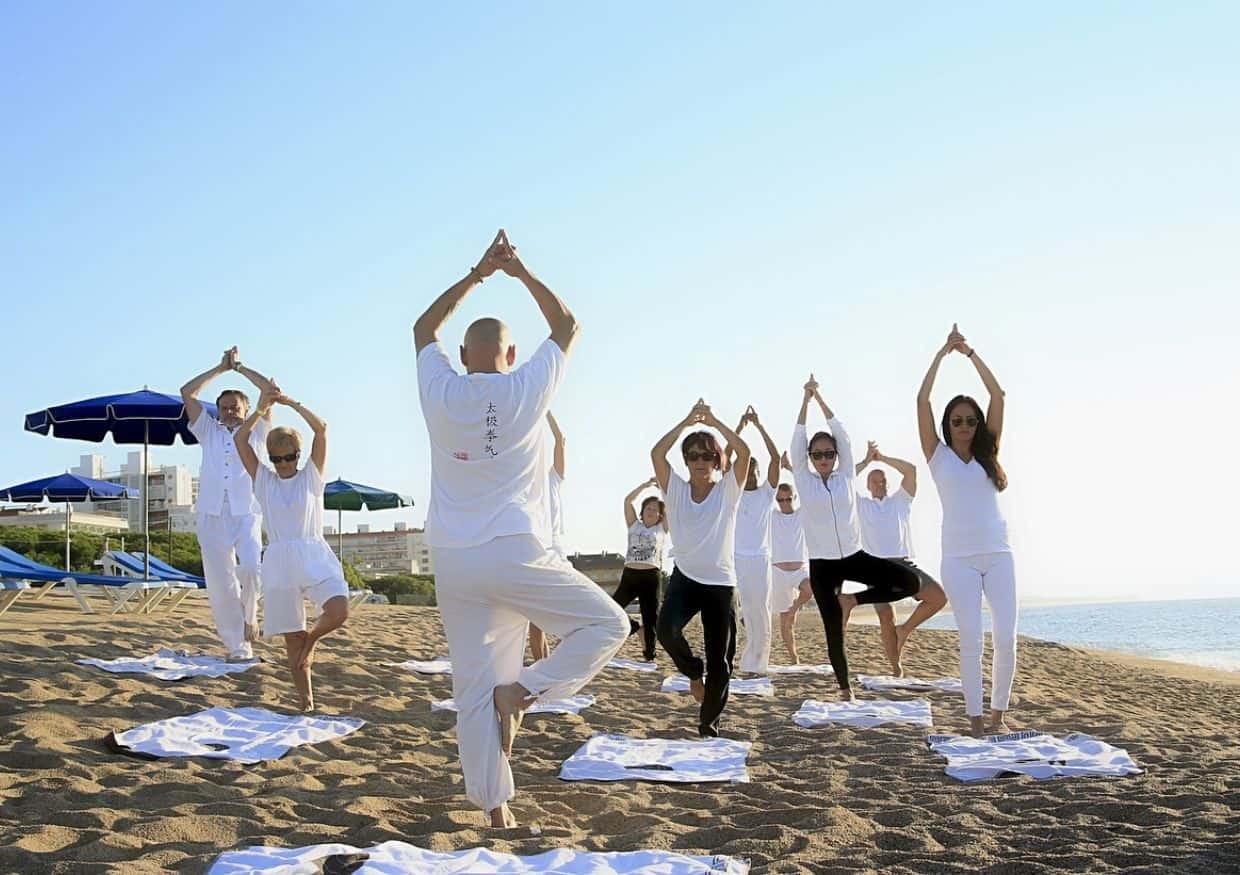 A group of people doing yoga on the beach.